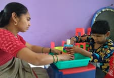 Child with deafblindness engaged in stacking tower activity with the support of her special educator